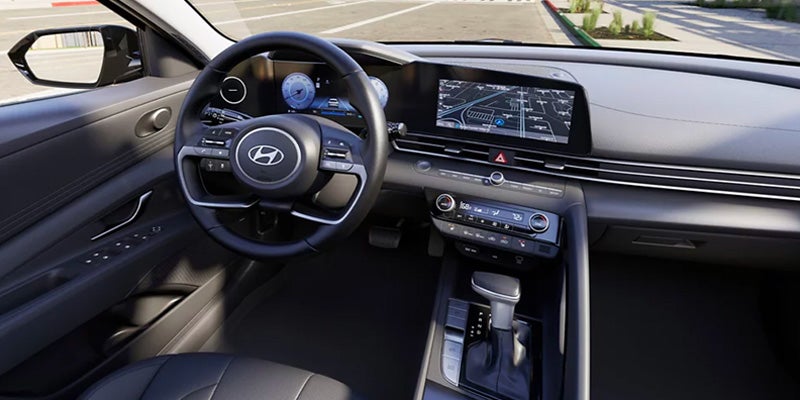 Dashboard and interior of a car, featuring a steering wheel, screen displays, and a gear shift.
